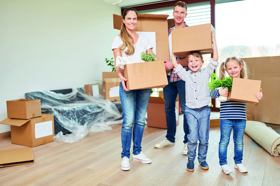 Eltern und Kinder tragen zusammen Umzugskartons in die neue Wohnung.