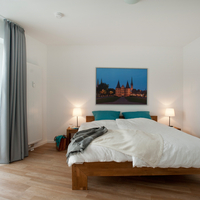 Schlafbereich mit Doppelbett Doppelbett aus Holz, Nachttische mit Nachttischlampen.