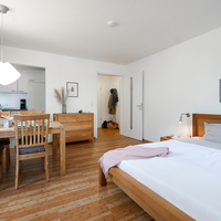 Wohnbereich der Gästewohnung mit Bett, Essplatz und Küche Wohnraum einer Gästewohnung mit Doppelbett, Esstisch und offener Küchenzeile